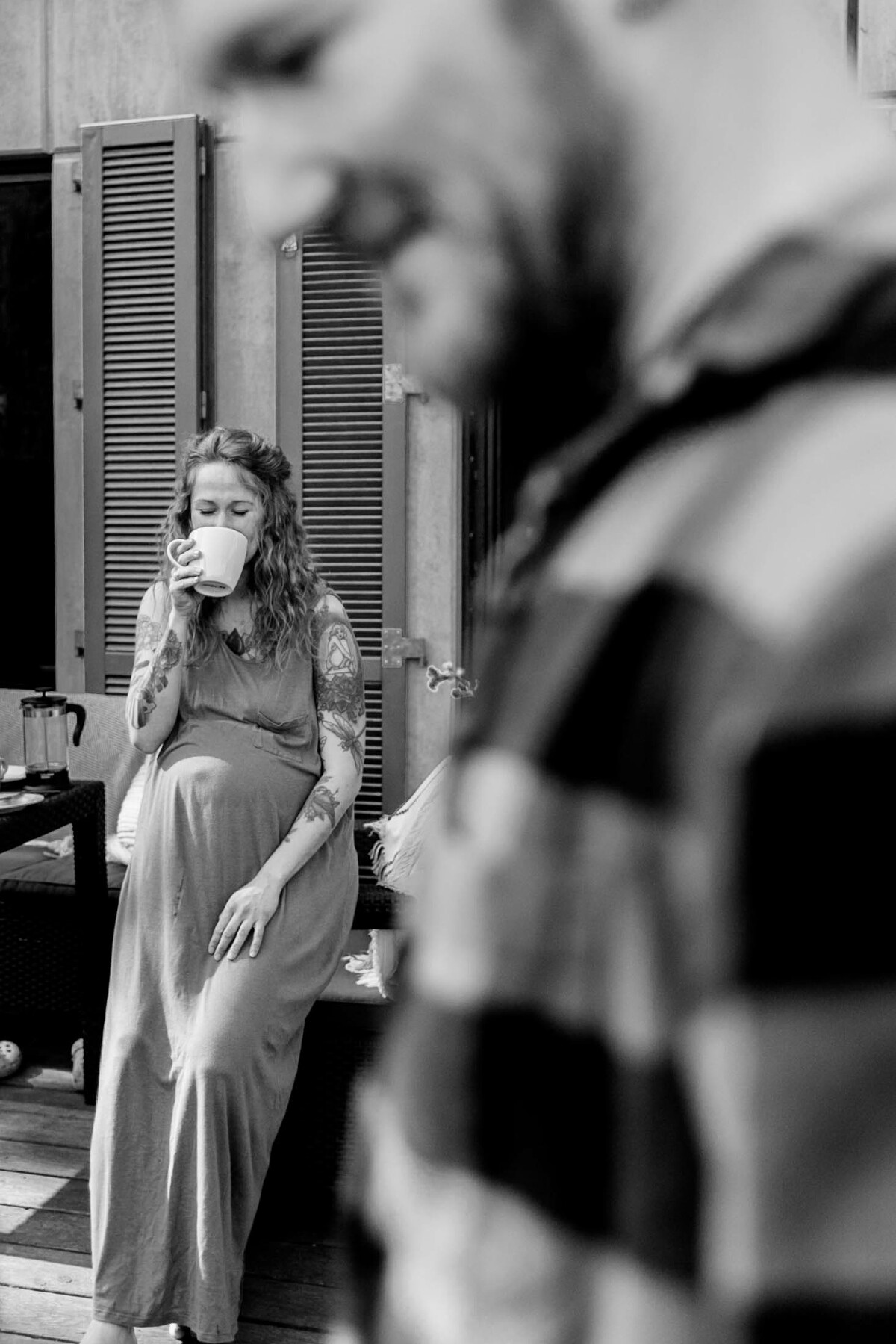 Schwangere Frau trinkt einen Kaffee, im Vordergrund der Mann