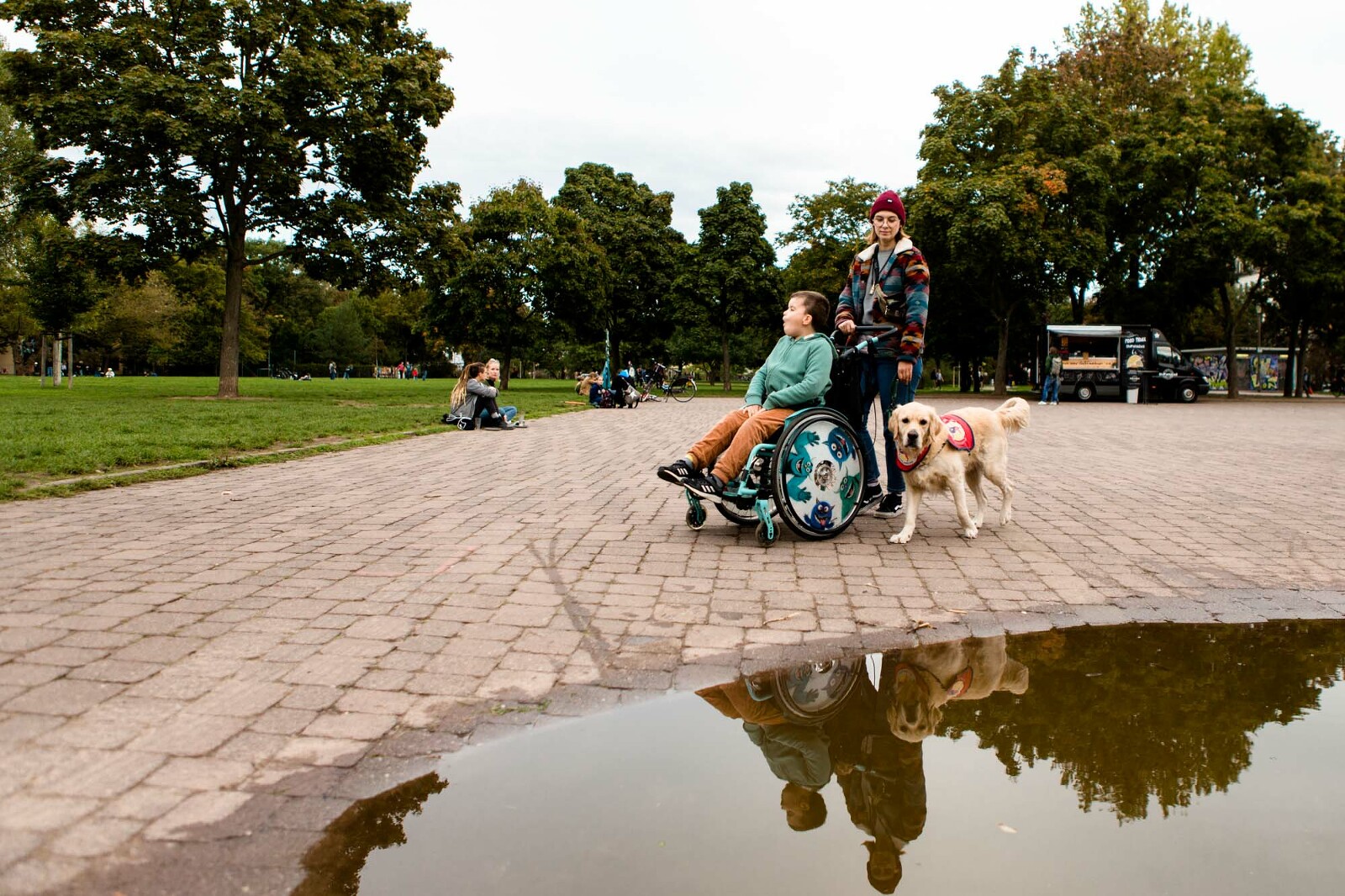 Mutter schiebt ihren Sohn im Rollstuhl durch den Park
