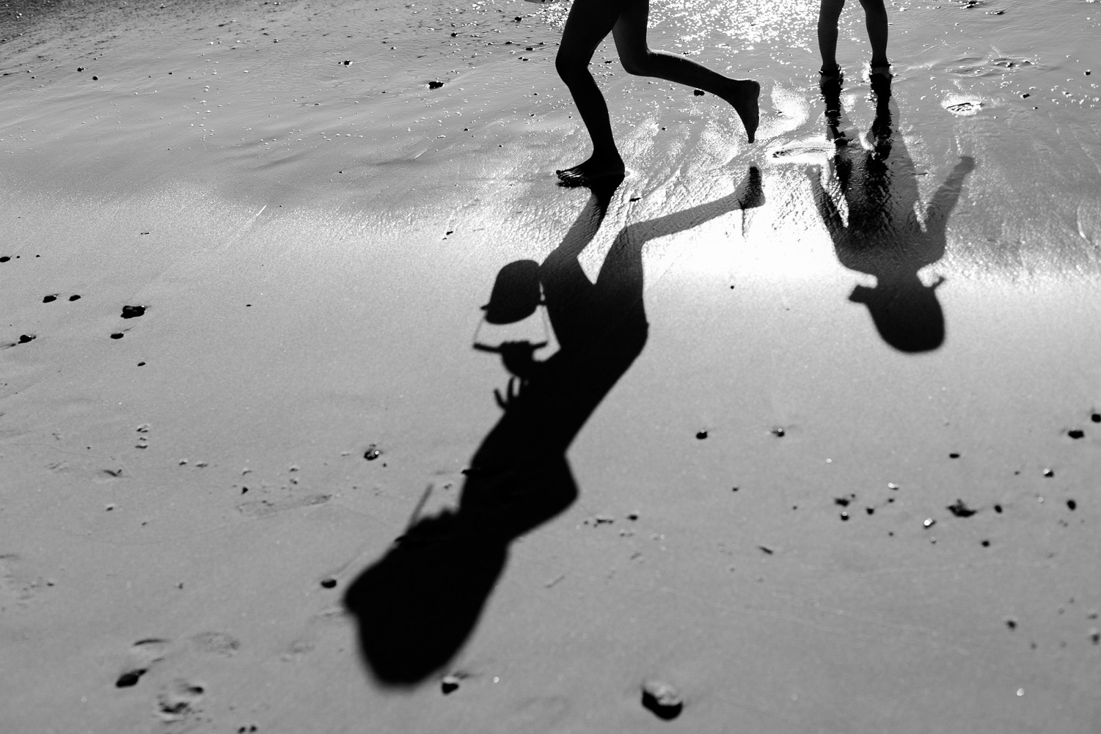 Der Schatten von Kindern, die über den Strand rennen